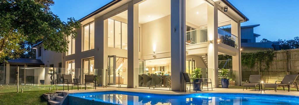 Modern two-story home with pool illuminated at twilight.