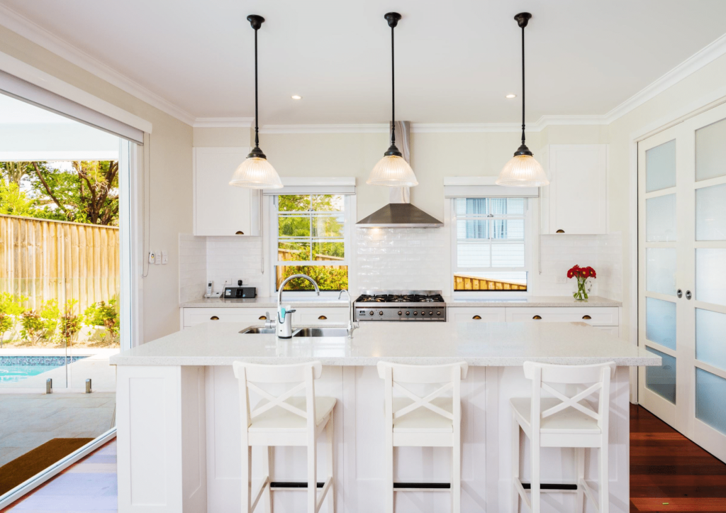 Modern kitchen with a white island, bar stools, and stainless steel appliances.