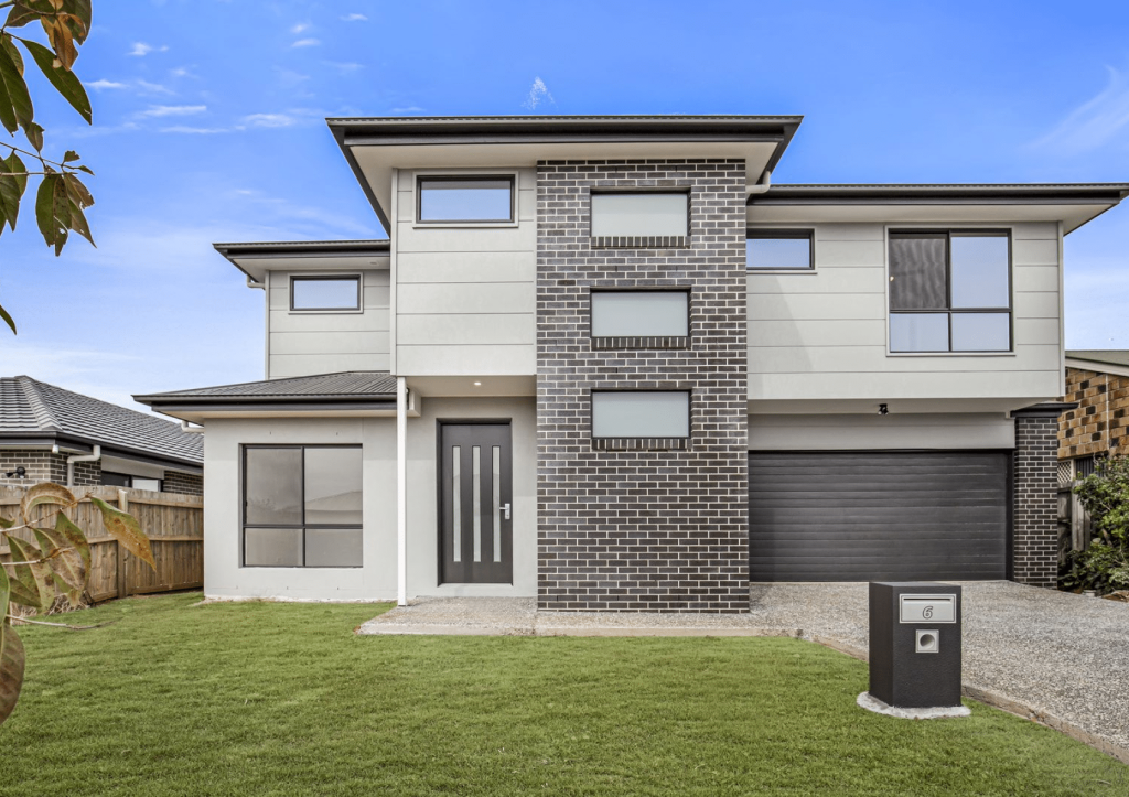Modern two-story residential house with brick facade and attached garage.