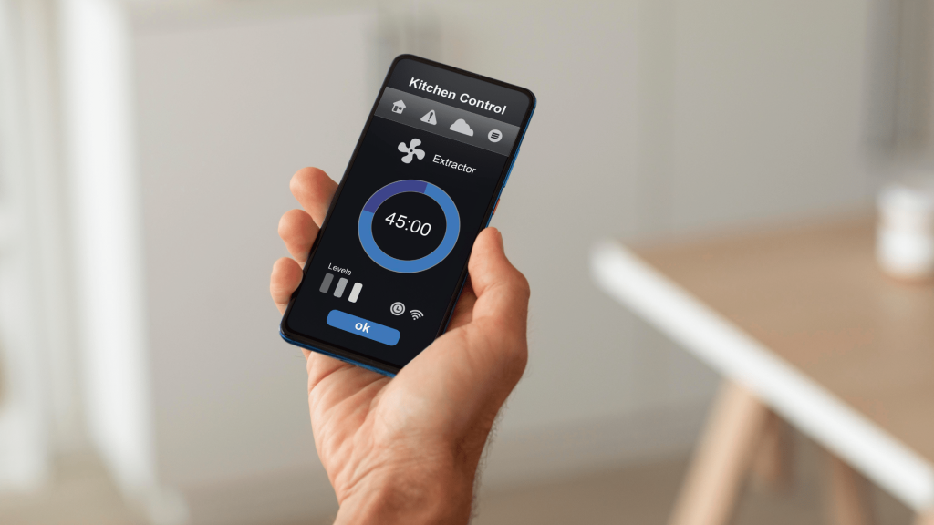 A person holding a smartphone with a kitchen appliance control app displayed on the screen.